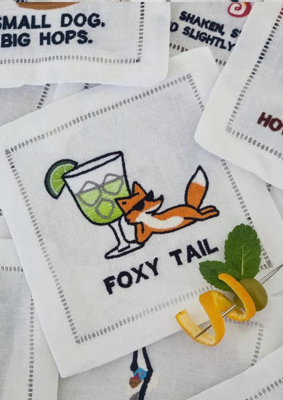 Linen cocktail napkin with a machine-embroidered fox and a lime cocktail